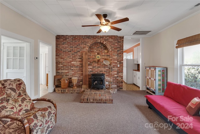 carpeted living room featuring a wood stove, ceiling fan, and ornamental molding