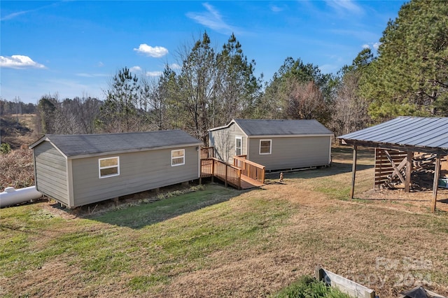 rear view of property featuring an outbuilding, a yard, and a deck