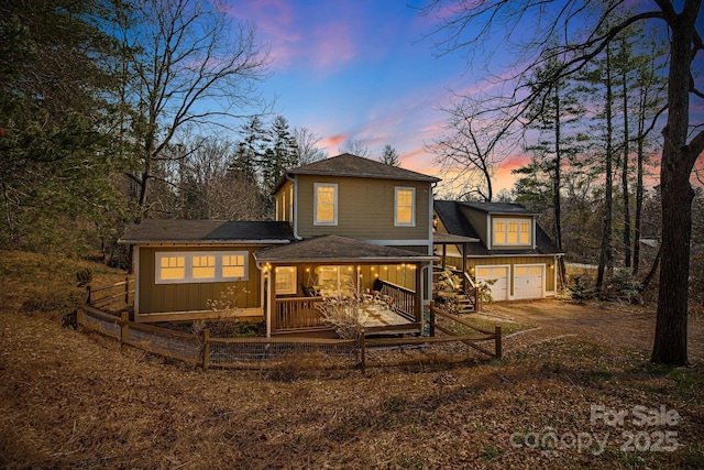 back house at dusk with a garage and a deck