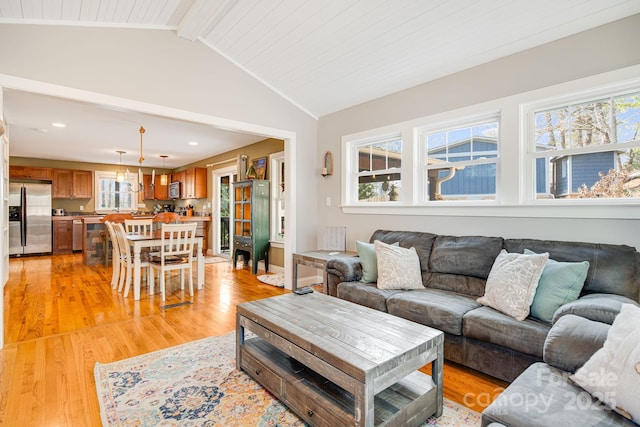 living room with vaulted ceiling with beams and light hardwood / wood-style floors