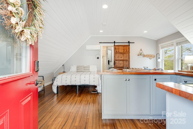 bedroom with lofted ceiling, hardwood / wood-style flooring, wood ceiling, a barn door, and a wall unit AC