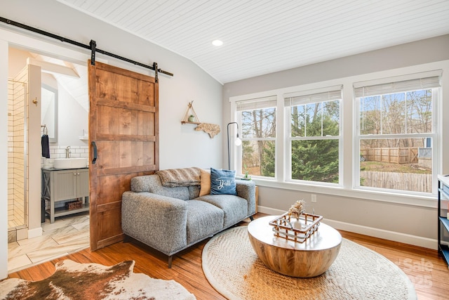 sitting room with sink, vaulted ceiling, light hardwood / wood-style flooring, wooden ceiling, and a barn door