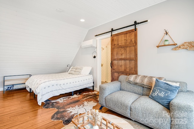 bedroom with hardwood / wood-style flooring, an AC wall unit, lofted ceiling, and a barn door