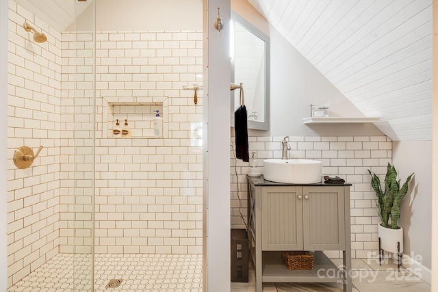 bathroom with lofted ceiling, vanity, an enclosed shower, and tile walls