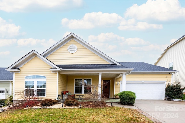 view of front of house featuring a front lawn, covered porch, and a garage