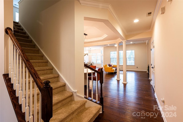 stairs featuring a chandelier, hardwood / wood-style floors, decorative columns, and ornamental molding