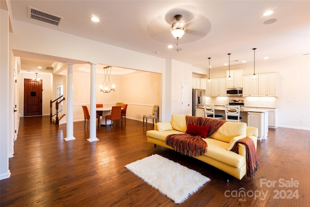 living room featuring ceiling fan with notable chandelier, dark hardwood / wood-style floors, and decorative columns