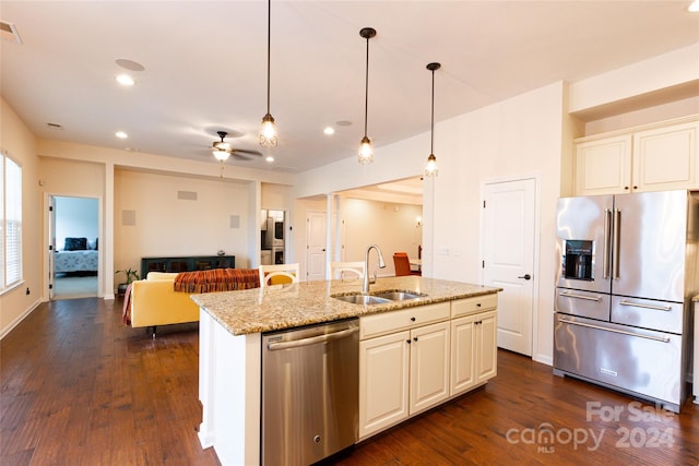 kitchen featuring light stone countertops, sink, stainless steel appliances, dark hardwood / wood-style floors, and an island with sink