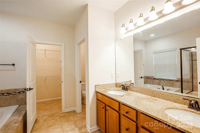 bathroom featuring tile patterned floors, vanity, toilet, and tiled bath