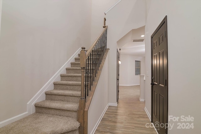 stairway featuring a towering ceiling and hardwood / wood-style flooring