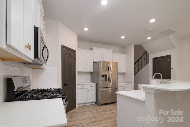 kitchen with a kitchen island with sink, light hardwood / wood-style flooring, white cabinets, and appliances with stainless steel finishes