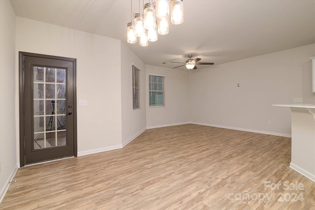 spare room with ceiling fan with notable chandelier and light hardwood / wood-style flooring