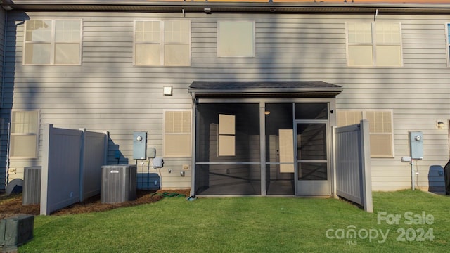 rear view of property with central AC unit, a sunroom, and a yard