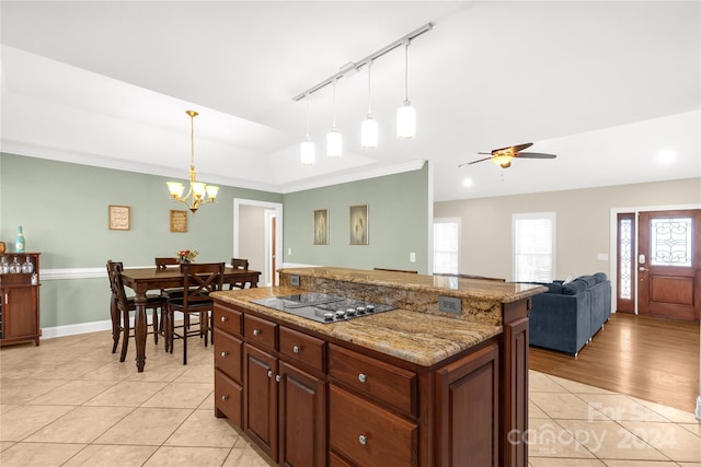 kitchen with a center island, pendant lighting, light tile patterned flooring, ceiling fan with notable chandelier, and electric stovetop