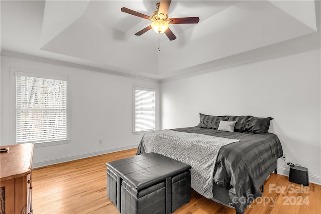 bedroom with light wood-type flooring, a raised ceiling, and ceiling fan