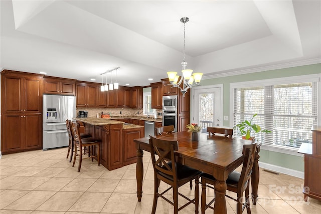 dining room featuring an inviting chandelier, light tile patterned floors, ornamental molding, and a tray ceiling