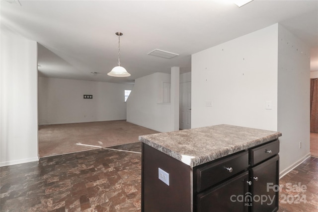 kitchen featuring a kitchen island, hanging light fixtures, and dark carpet