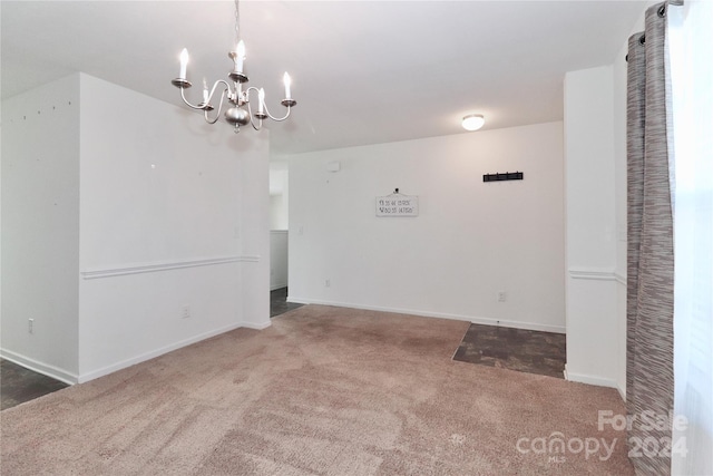 carpeted spare room with a chandelier