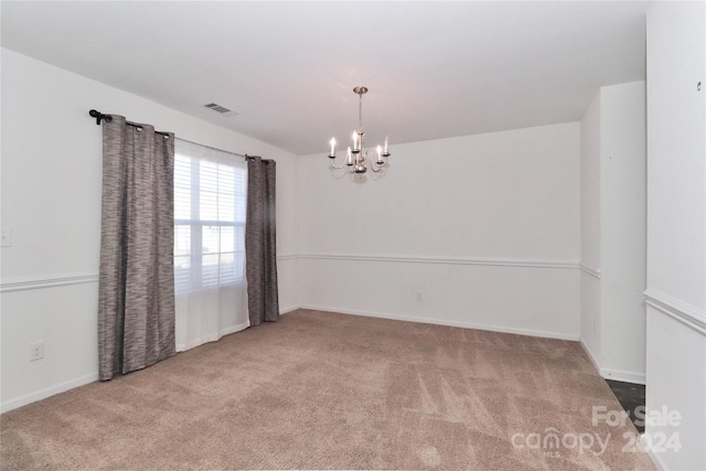 empty room featuring carpet floors and a chandelier