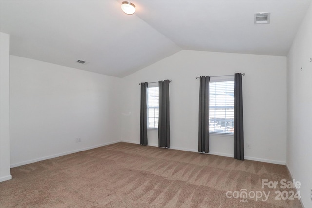 carpeted spare room featuring vaulted ceiling