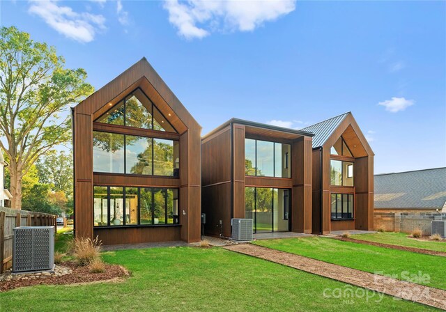 back of property featuring a yard and central AC