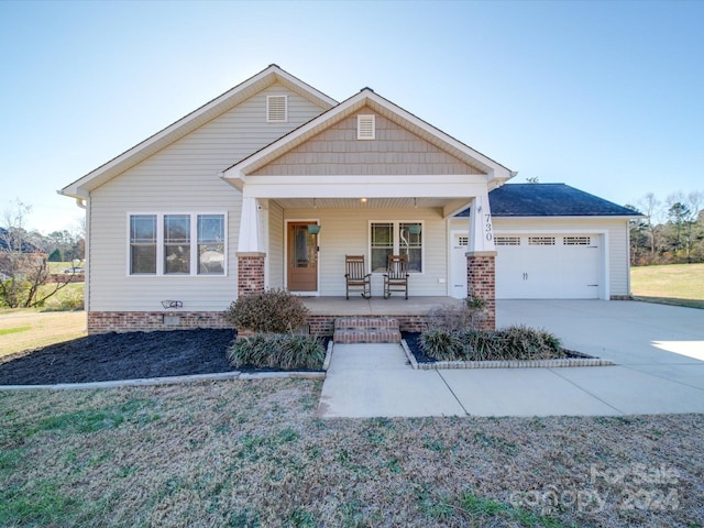 craftsman house with covered porch, a garage, and a front yard