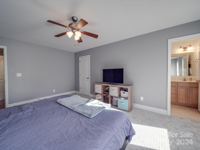 bedroom featuring ceiling fan, ensuite bathroom, light carpet, and sink