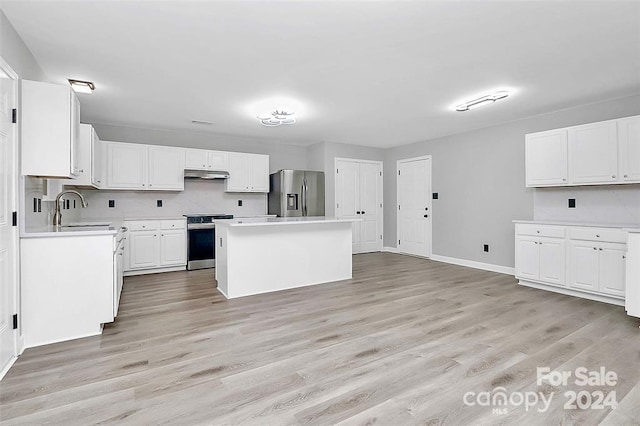 kitchen with appliances with stainless steel finishes, sink, light hardwood / wood-style flooring, white cabinets, and a center island