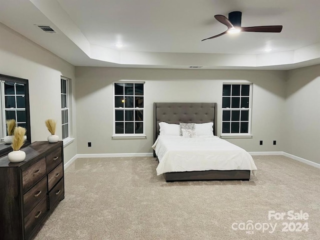 carpeted bedroom featuring a raised ceiling and ceiling fan