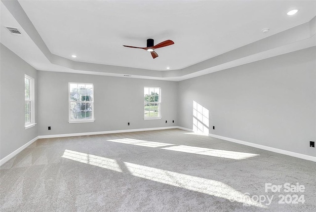 carpeted spare room with ceiling fan and a raised ceiling