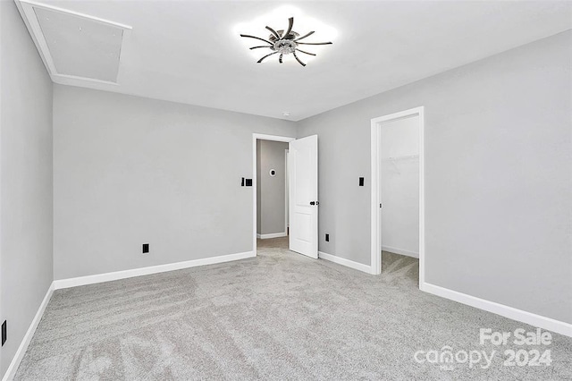 unfurnished bedroom with a spacious closet, a closet, and light colored carpet