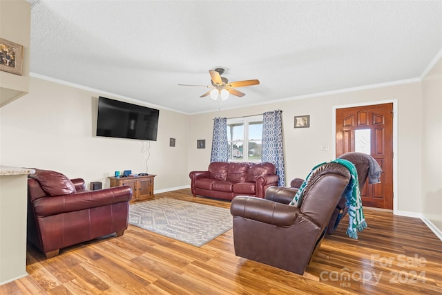 living room with ceiling fan, hardwood / wood-style floors, a textured ceiling, and ornamental molding