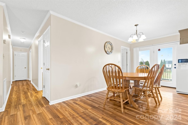 dining area featuring a chandelier, wood-type flooring, a textured ceiling, and crown molding