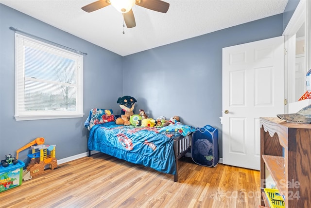 bedroom with ceiling fan, a textured ceiling, and light wood-type flooring