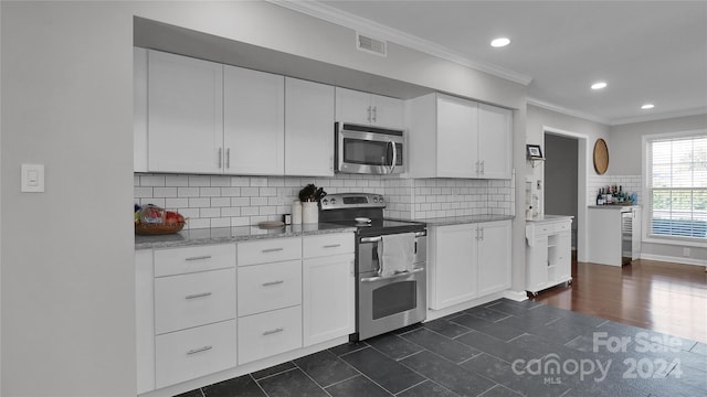 kitchen featuring tasteful backsplash, light stone counters, crown molding, white cabinets, and appliances with stainless steel finishes