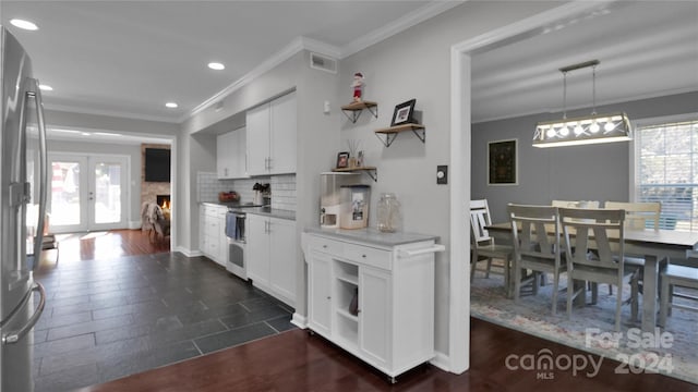 kitchen with stainless steel fridge, white cabinetry, and a wealth of natural light