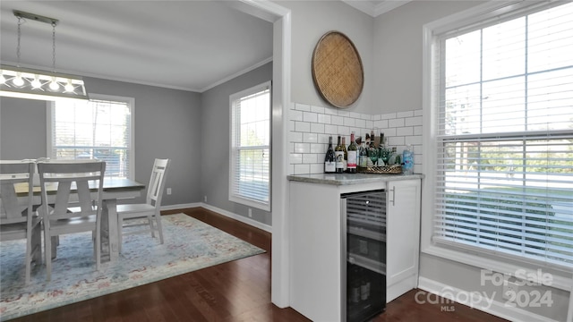 dining room featuring plenty of natural light, crown molding, and beverage cooler