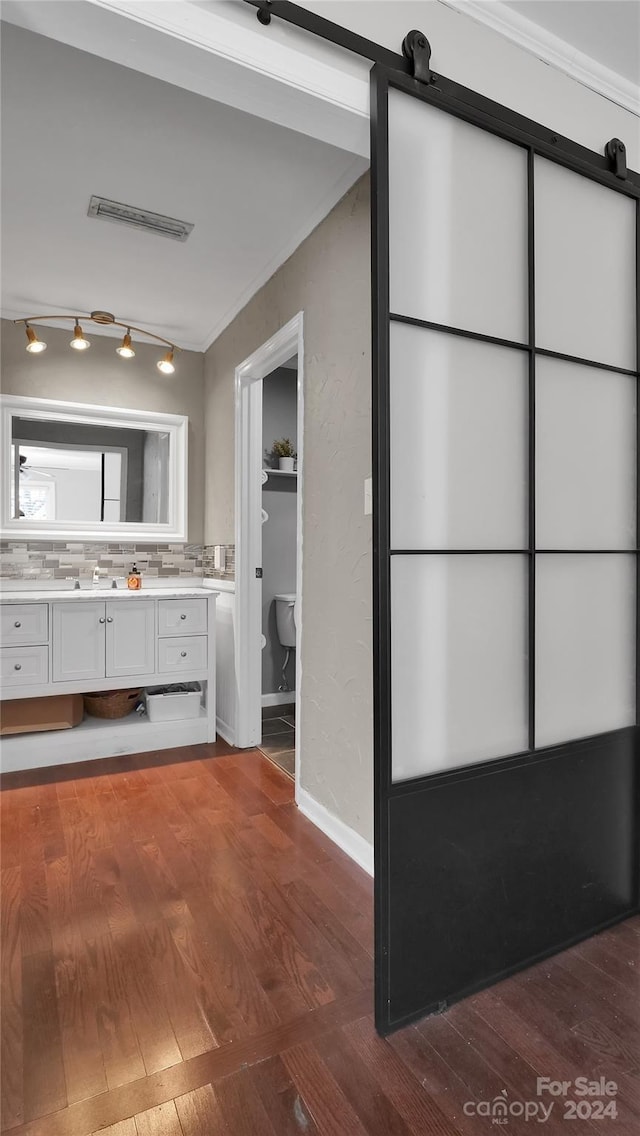 bathroom featuring vanity, backsplash, toilet, ornamental molding, and wood-type flooring