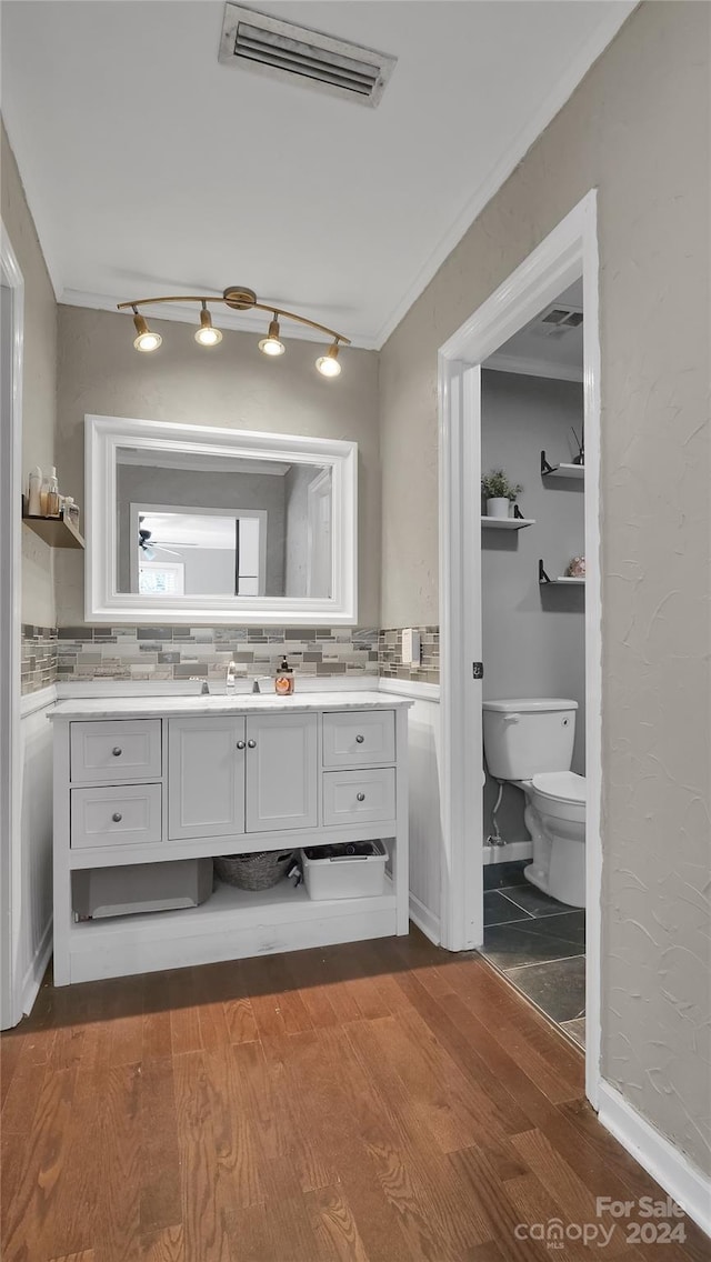 bathroom with hardwood / wood-style floors, vanity, tasteful backsplash, and crown molding