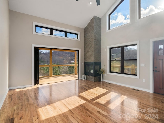 154 Aster Ridge Dr, Waynesville, NC 28786 - unfurnished living room featuring a high ceiling, a stone fireplace, wood finished floors, and ceiling fan