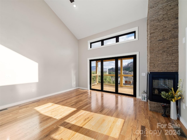 unfurnished living room featuring hardwood / wood-style flooring, a fireplace, and high vaulted ceiling