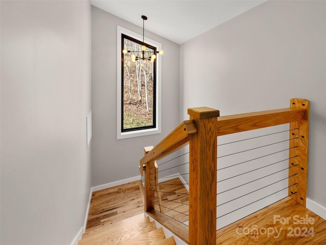 staircase with hardwood / wood-style flooring and a notable chandelier