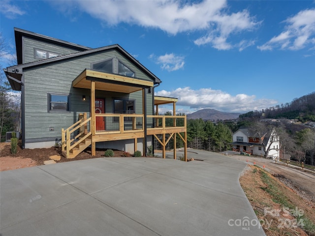 view of front facade with a mountain view, cooling unit, and covered porch