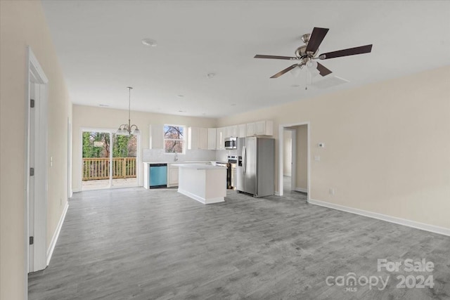 unfurnished living room with ceiling fan with notable chandelier and light hardwood / wood-style flooring