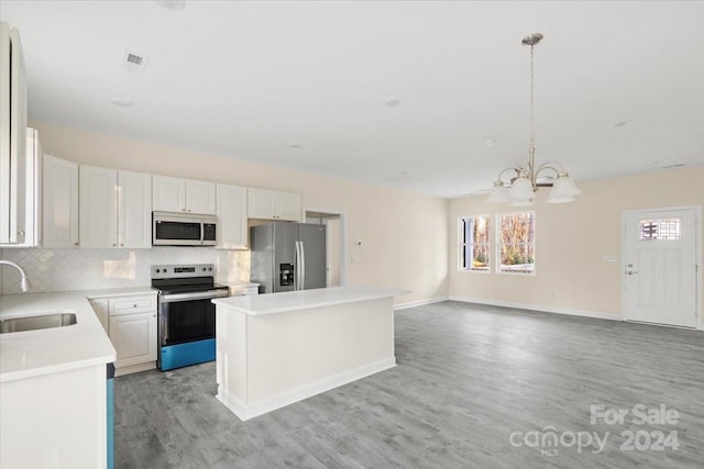 kitchen featuring pendant lighting, a center island, light wood-type flooring, appliances with stainless steel finishes, and white cabinetry