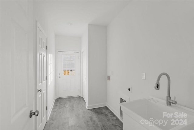 washroom featuring electric dryer hookup, sink, and light hardwood / wood-style flooring