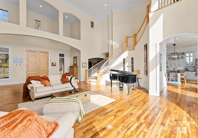 living room with a wealth of natural light, light hardwood / wood-style flooring, a high ceiling, and ornamental molding