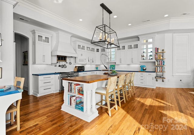 kitchen featuring butcher block countertops, white cabinetry, hardwood / wood-style flooring, and custom exhaust hood