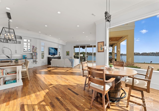 dining room featuring light hardwood / wood-style floors, crown molding, a healthy amount of sunlight, and sink