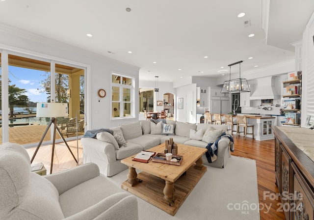 living room featuring light hardwood / wood-style flooring, crown molding, and a notable chandelier